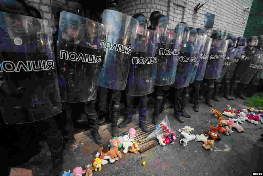 Дитячі іграшки біля строю поліцейських, які стоять на сторожі поліцейської дільниці в Переяславі-Хмельницькому. Місцеві протестують через смерть 5-річного хлопчика Кирила Тлявова від кулі поліцейських (за даними слідства). Переяслав-Хмельницький, Київська область, 4 червня 2019 року