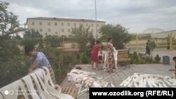 Учителя чистят жалюзи во дворе школы.