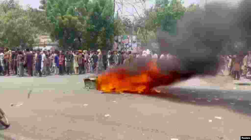 People stand near burning objects taken from a church in Jaranwala on August 16.