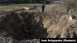 Місцевий житель дивиться на воронку на місці російського ракетного удару, Херсон, 5 грудня 2023 року