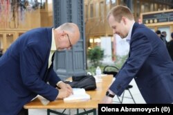Український письменник Андрій Курков на книжковому форумі у Брюсселі підписує книгу для польського шанувальника