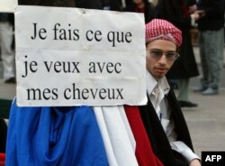 مخالفان قانون لائیسیته در فرانسه با پلاکاردی که روی آن نوشته: «با موهایم هر کاری که بخواهم می‌کنم»