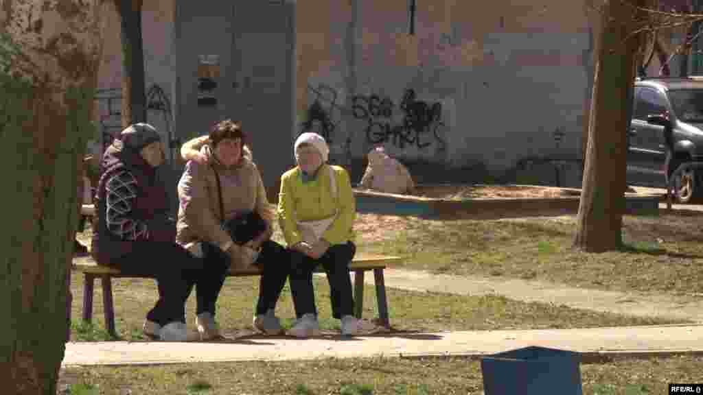 Жительницы Харькова, города на северо-востоке Украины, сидят на скамейке в солнечный день во время затишья в обстрелах. 1 апреля 2024 года. Город после начала войны стал объектом интенсивных российских бомбардировок, которые уничтожают его инфраструктуру