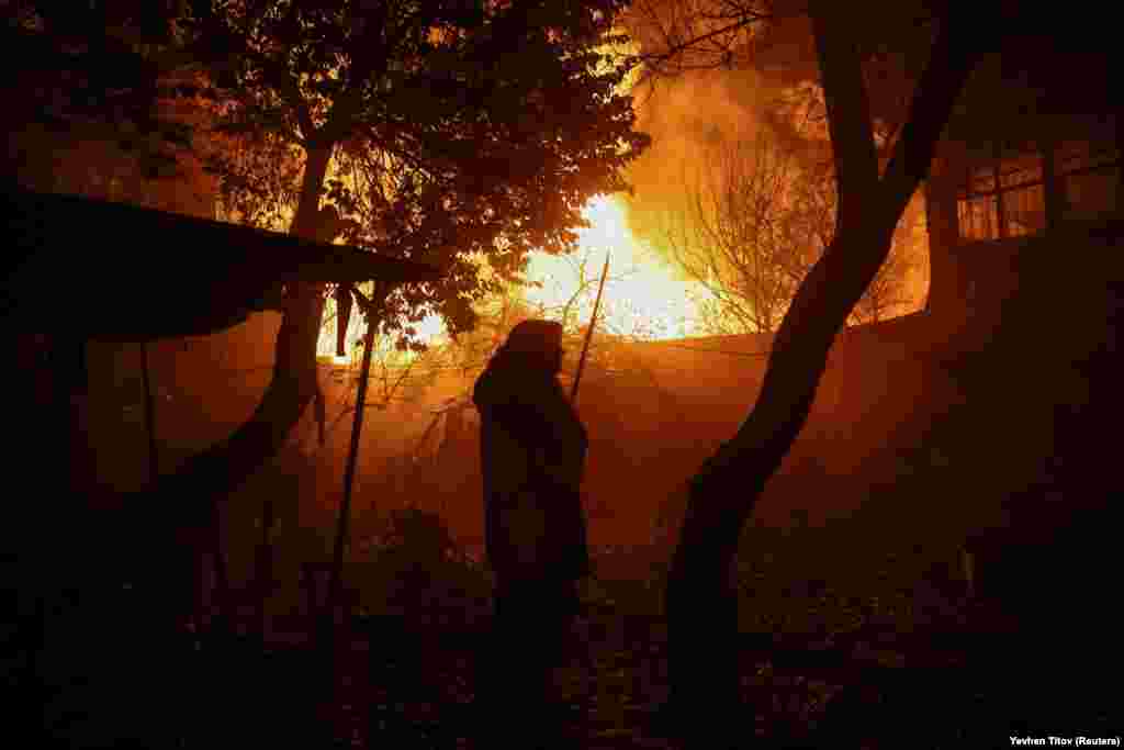 A resident looks on as homes burn. The latest wave of Russian air strikes on infrastructure comes as fears mount that Moscow is trying to cripple Ukraine&#39;s energy grid as temperatures plummet&nbsp;in winter.