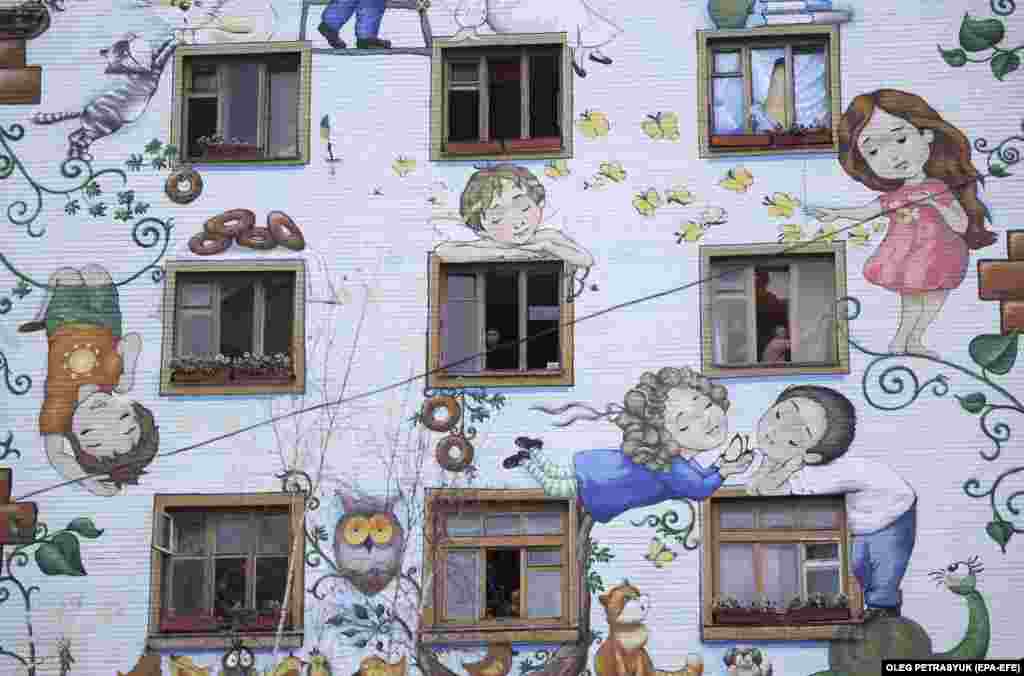 Мешканці будинку прибирають розбите скло з вікон своїх квартир після обстрілу столиці Росією, Київ, 23 січня 2024 року &nbsp;