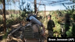 Український військовий несе снаряд до гаубиці на околиці Лиману, 15 серпня 2023 року