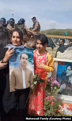 شرمین حبیبی بر آرامگاه مهسا در حالی که تصویری از همسرش فریدون محمودی را در دست دارد