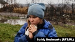9 жасар қыз Софийка Луганск облысының шығысындағы Макеевкадан эвакуациялау кезінде теңіз шошқасын құшақтап тұр. 2022 жылғы 19 қараша.