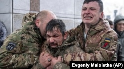 Ukrainian soldiers cry near the coffin of a comrade during his funeral service on Independence Square in Kyiv on December 15, 2023.