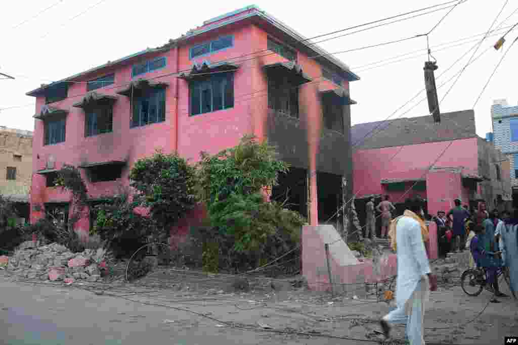 People gather outside a damaged church on the outskirts of Faisalabad.
