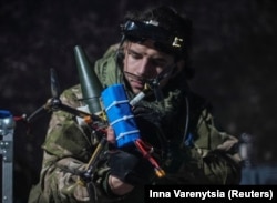 Український військовослужбовець батальйону ударних безпілотників 92-ї бригади «Ахілл» прикріплює снаряд до безпілотного літального апарату для огляду від першої особи (FPV) у Донецької області, Україна. 2 лютого 2024 року