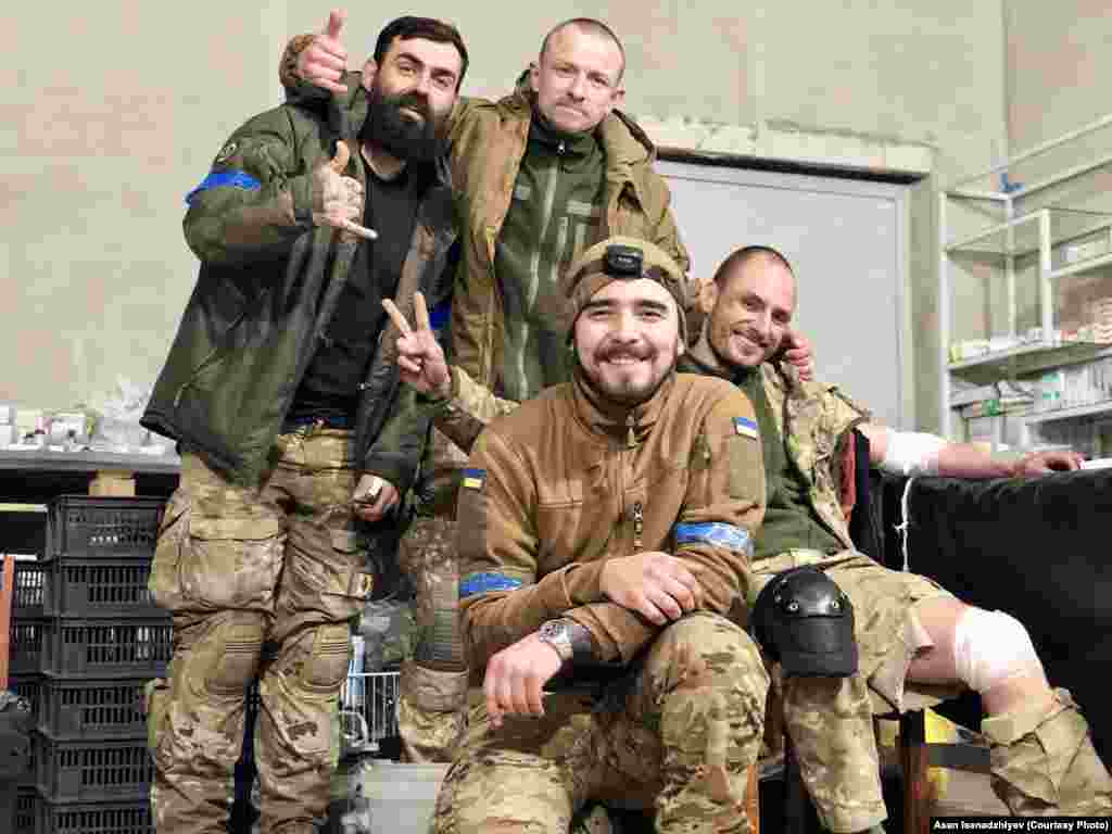 Mariupol, 2022 senesi. Merkezde - Azatlıq Radiosına bu fotoresimlerni bergen qırımlı, arbiy ekim Asan İsenacıyev. O, &quot;Azovstal&quot;den 2022 senesi mayıs ayında, Rusiye ordusı sarıp alğan zavodda qalğan soñki ukrayin bölükleri ile çıqtı. Bundan soñ o, diger askerlernen beraber Olenivka koloniyasına qapatıldı ve esirler ile baraknıñ patlavı vaqtında sağ qaldı. 2022 senesi dekabrniñ 31-nde Asanı deñiştirdiler. Bu fotoresimde &quot;Vışnâ&quot;, &quot;Şprot&quot; ve &quot;Grân&quot; (soldan sağğa) arbiyler onıñnen beraber turalar. Olar sarıp alınğan Mariupolge tikuçarnen kirdiler. Olardan tek Vişnâ sağ qaldı, o da Rusiye esirliginden keçti, almaşuvdan soñ ise orduğa qayttı. Şprot ve Grân 2022 senesi baarde Mariupolde elâk oldılar