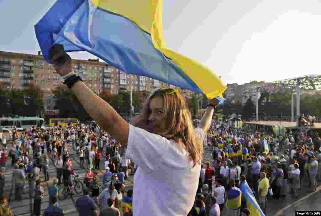 Серпень 2014 року. Український стяг майорить в руках учасниці проукраїнського мітингу в Маріуполі. Влада України контролювала Маріуполь майже 8 років. На початку повномасштабного вторгнення Росії Маріуполь опинився в оточенні армії РФ. Місто було майже повністю знищене внаслідок невпинних обстрілів російської армії. Під час облоги та тяжких боїв за Маріуполь там загинули десятки тисяч людей. Тільки серед цивільних, за даними міського голови Вадима Бойченка, кількість загиблих сягає 20 тисяч. Реальна цифра може бути більшою &ndash; точно встановити її наразі неможливо