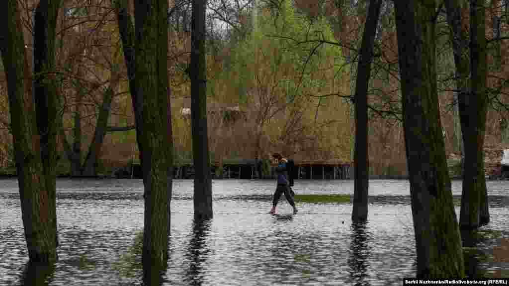 Деякі люди пересуваютсья затопленими районами босоніж