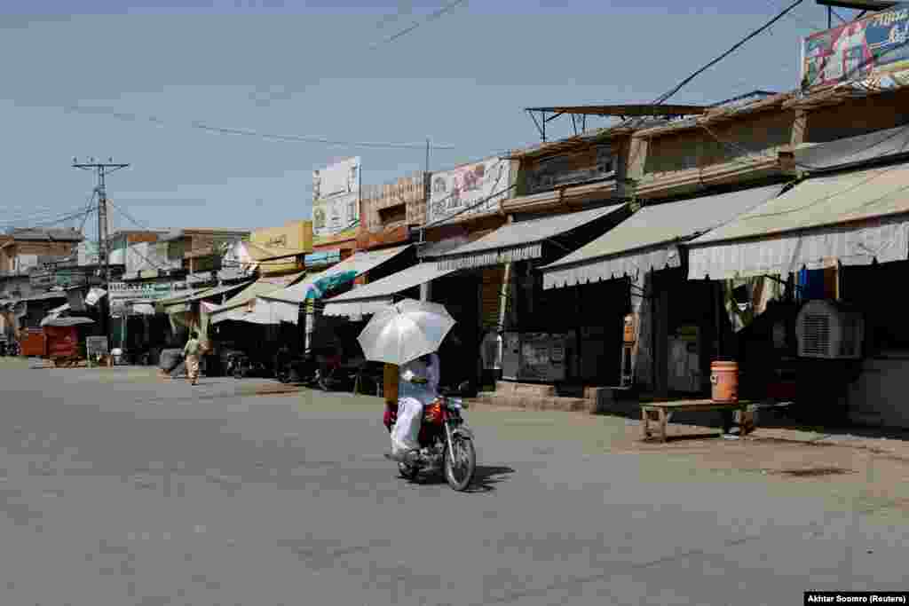 زوج سوار بر موتور در راستهٔ بازاری قدیمی در یعقوب&zwnj;آباد حرکت می کنند؛ افزایش دما باعث شده ایالت پنجاب مدارس را تعطیل کند و حداقل ۲۶ میلیون دانش&zwnj;آموز به مدرسه نروند. 