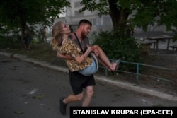 Хлопець несе на руках дівчину, поранену внаслідок російського ракетного удару по Покровську, 7 серпня 2023 року