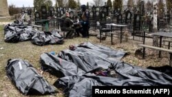 Поліцейські поруч із тілами загиблих під час російської окупації Бучі на місцевому кладовищі, квітень 2022 року