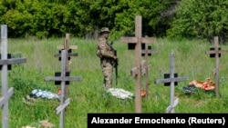 Ресей әскери қызметкерлерін жерлеу рәсімінде зиратты күзетіп тұрған сарбаз. Луганск, Украинаның Ресей бақылауындағы бөлігі. 18 мамыр, 2023 жыл.