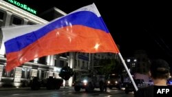 A man waves the Russian flag as members of Wagner Group prepare to pull out from the headquarters of the Southern Military District in Rostov-on-Don to return to their base late on June 24.
