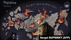 Український військовий проходить повз банер у Києві, Україна.