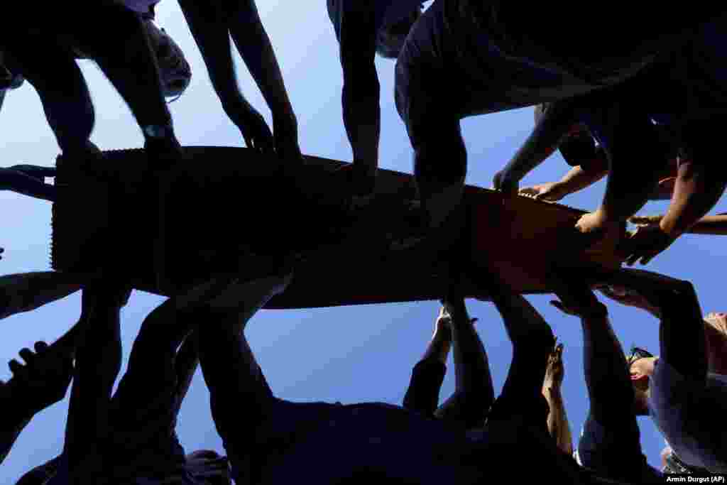 Muslim men carry coffins containing the remains of recently identified victims of the 1995 Srebrenica genocide. Among the remains are those of four minors who were 15 and 16 years of age when they were killed.