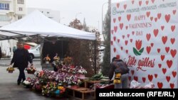 Türkmenistanda Keramatly Walentin, ýagny Söýgüliler gününe degişli plakatyň öňünde gül satýan söwda tekjeleriniň biri (Illýustrasiýa suraty)