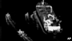 An image taken from surveillance video from a U.S. Navy Boeing P-8 Poseidon shows three IRGC fast-attack vessels near a commercial ship in the Strait of Hormuz in June.