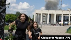 A family runs from an explosion after a Russian missile strike on a residential neighborhood in Pervomayskiy, in Ukraine's northeastern Kharkiv region, on July 4.