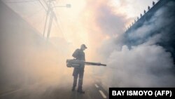 یک مأمور امدادی در حال ضدعفونی خیابانی در جاکارتا با هدف مقابله با پشه‌های ناقل تب دنگی