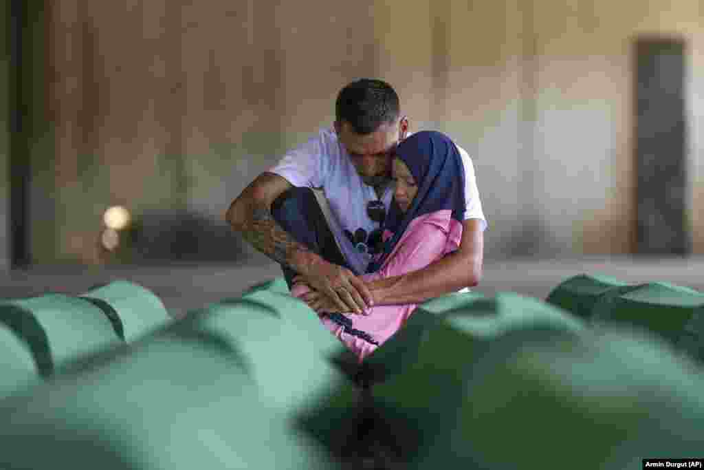 Samed Alic mourns with his daughter next to the coffin containing the remains of his father at the Srebrenica-Potocari Memorial Center on July 10.