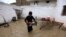 A boy rescues belongings from a flooded home after heavy rains in Peshawar, Pakistan, in April.