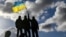 U.K. – Ukrainian personnel hold a Ukrainian flag as they stand on a Challenger 2 tank during training at Bovington Camp, near Wool in southwestern Britain, February 22, 2023