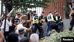 Police officers intervene following the burning of a Koran outside Stockholm's central mosque on June 28.