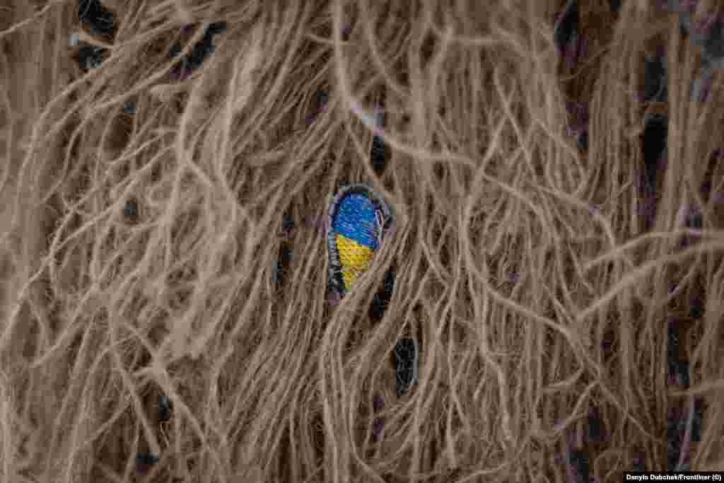 Маленька нашивка з українським прапором, захована всередині кікімори. Катерина служить в українській армії вже понад п&#39;ять років, проте не планує залишатися у війську після перемоги України. &laquo;Я хочу подорожувати по світу, хотіла б ще раз поїхати в Іспанію, Фінляндію, Америку&raquo;, &ndash; каже вона. Найважче, за її словами, визнати той факт, що війна, яку розпочала Росія, навряд чи закінчиться найближчим часом. &laquo;Ти робиш великий вклад у це і ти не розумієш, де межа, і чи ти взагалі доживеш до цієї межі&raquo;, &ndash; каже вона. Ця фотогалерея є адаптованою версією репортажу Олени Максименко та Данило Дубчака, яку вперше опублікував Frontlineer