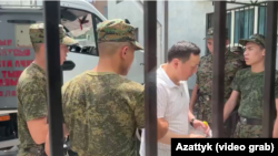 Один из фигурантов Кемпир-Абадского дела возле здания суда под конвоем. Бишкек, 22 июня 2023 года