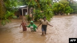 Гаитинин Леоган шаарынын тургундары суу каптаган көчөдө баратышат. 3-июнь, 2023-жыл.