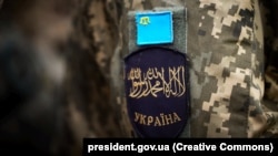 Ukrayin musulman cemiyetiniñ vekillerinen beraber Ukrayina prezidenti de iştirak etken iftarda iştirak etkenniñ şevronı. Kıyiv, 2024 senesi saban ayınıñ 25-i