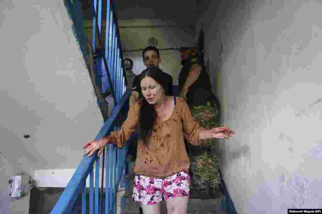 An injured woman runs down a staircase.