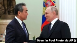 Russian President Vladimir Putin (right) greets Chinese foreign policy chief Wang Yi at the Kremlin in Moscow on February 22. The United States and NATO have accused China of considering supplying arms to Russia.