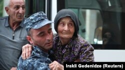 Арменски полицай помага на бежанка от Нагорни Карабах, която пристига в центъра за временно настаняване в град Горис, Армения, 24 септември 2023 г. 