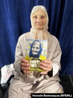 Олександра Васейко тримає книжку «Оповідання з Волині», в якій йдеться про неї та її батька