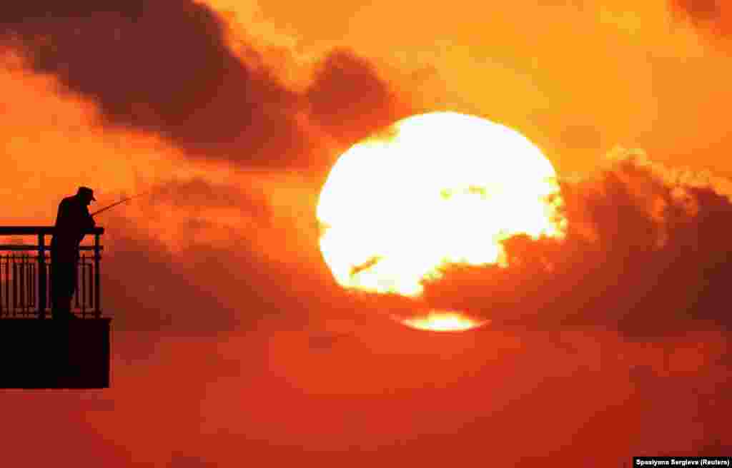 Болгария, Бургас шаары. Кара деңиз жээгинде пристанда балык кармап жаткан киши.