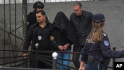 The suspect in the shooting, his head covered by a coat, is escorted by police outside the Vladislav Ribnikar Elementary School in Belgrade on May 3.