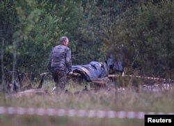 Куткаруучулар учак кыйраганда мүрт кеткендердин сөөгүн алып баратат.