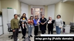 Кайтарылган ымыркайларды министрликтин кызматкерлери кармап турушат. 