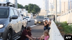 چند شهروند اسرائیلی بدنبال آژیر خطر حمله راکتی پناه گرفته‌اند