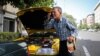 A taxi driver in Iran splashing water on her face on a hot day