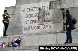 Люди фотографируют поврежденный знак памятника Советской армии в центре Софии 23 февраля 2023 года, накануне первой годовщины масштабного вторжения России в Украину.