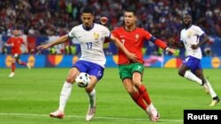 Франция ойыншысы Уильям Салиба (17) мен Португалия ойыншысы Криштиану Роналду (7) допқа таласып жатыр.  Гамбург, 6 шілде 2024 жыл.