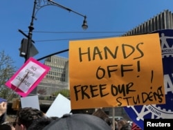 Колумбия университетинин студенттери куугунтукка каршы жазуулары бар кагазды көтөрүп баратышат. 1-май, 2024-жыл.